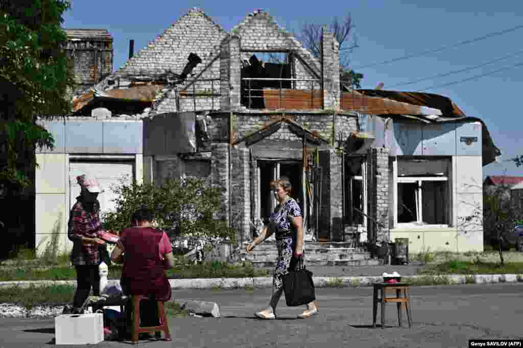 A woman buys products from a street vendor in front of a heavily damaged building in the eastern Ukrainian frontline town of Lyman, in the Donetsk region, on July 17. General Oleksandr Syrskiy, commander of Ukrainian ground forces, said on the Telegram messaging app on July 18 that Kyiv&#39;s troops faced challenges as they continued to register successes in their counteroffensive against Russian forces. &quot;The situation is difficult but under control (in the east),&quot; he said.&nbsp;