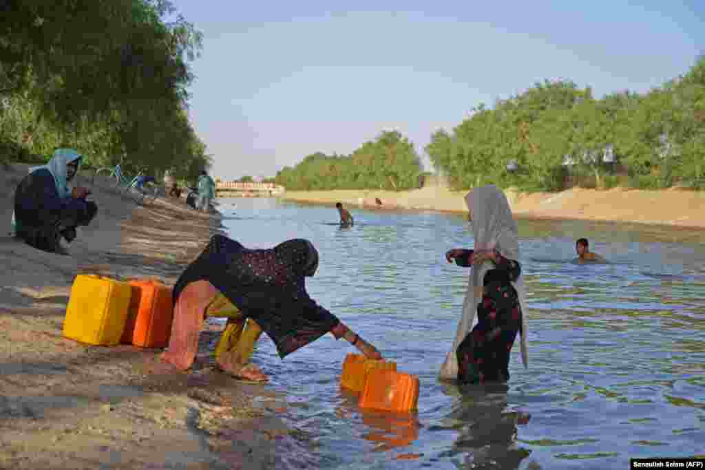 Afghan girls fill containers with water from a canal on the outskirts of Kandahar.&nbsp;