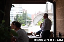 Waiter Aaron Berisha and customers go about their business with the bridge over the Ibar River visible outside Ura's window.