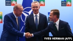 Turkish President Recep Tayyip Erdogan (left) and Swedish Prime Minister Ulf Kristersson shake hands in front of NATO Secretary-General Jens Stoltenberg prior to their meeting on the eve of the NATO summit in Vilnius on July 10.