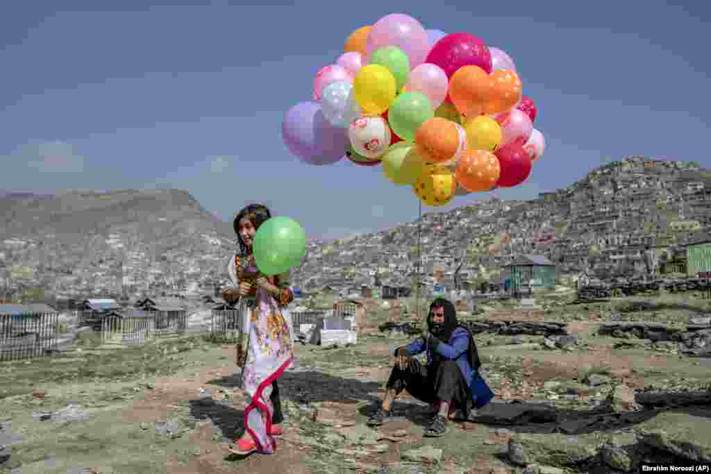 A girl buys a balloon for the Norouz celebration from a vendor at a cemetery in Kabul. The Taliban canceled the public holiday, though the militants have insisted those who wish to celebrate will not be prevented from doing so.