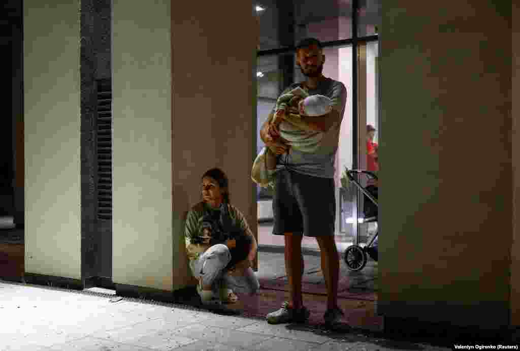 Kyiv resident Dmytro holds his 6-month-old daughter, Alina, while his wife holds their dog outside an apartment building damaged during the attack.