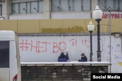 Workers paint over graffiti saying "#No to war" in Lipetsk, western Russia.