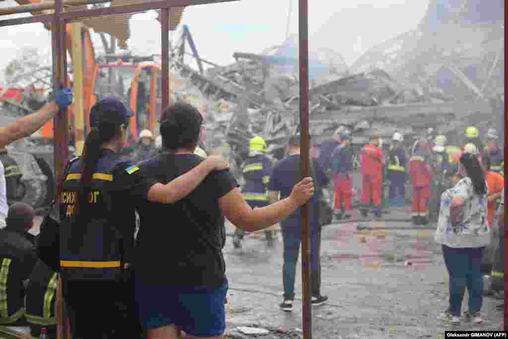 A rescue worker comforts a woman whose son&#39;s body was later found as emergency services comb through the rubble.