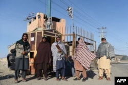 Taliban fighters stand guard at the entrance gate to an Afghan-Iran border crossing bridge in Zaranj.