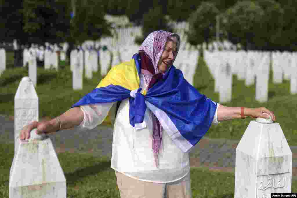 A Bosnian Muslim woman mourns next to the graves of her children and husband on July 11.