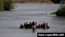 Migrants cross the Rio Grande River from Mexico into the United States at Eagle Pass, Texas, on May 20, 2022.