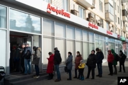 People stand in line to withdraw money from an ATM of Alfa Bank in Moscow on February 27, 2022, four days after Russia launched its unprovoked invasion of Ukraine.
