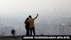 An Iranian couple takes a selfie as smog obscures the skyline in Tehran earlier this year. 