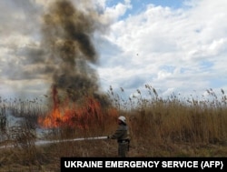 A firefighter extinguishes a fire in a wheat field in the Kherson region on July 18, 2022.