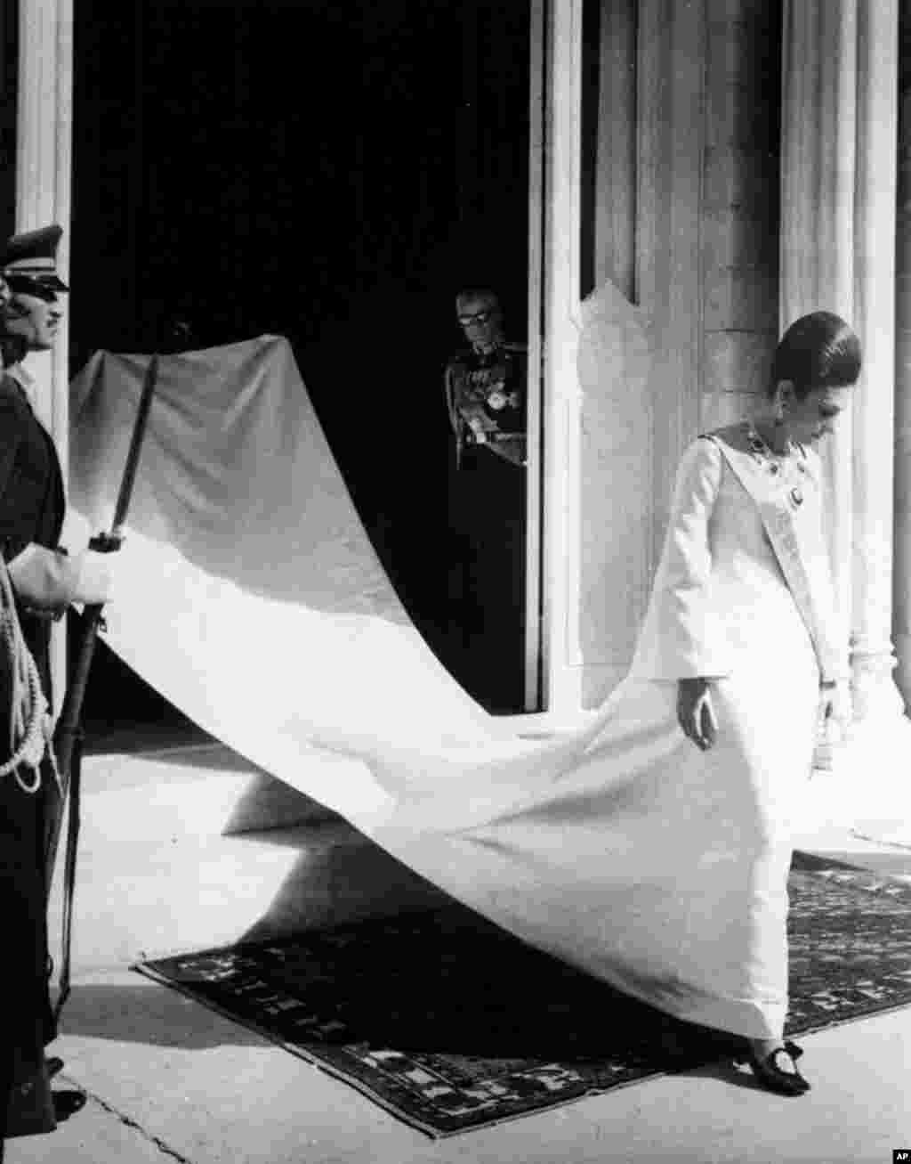 Empress Farah leaves the Marble Palace in Tehran in October 1967 for the coronation procession to the Golestan Palace. Her husband watches from the doorway.