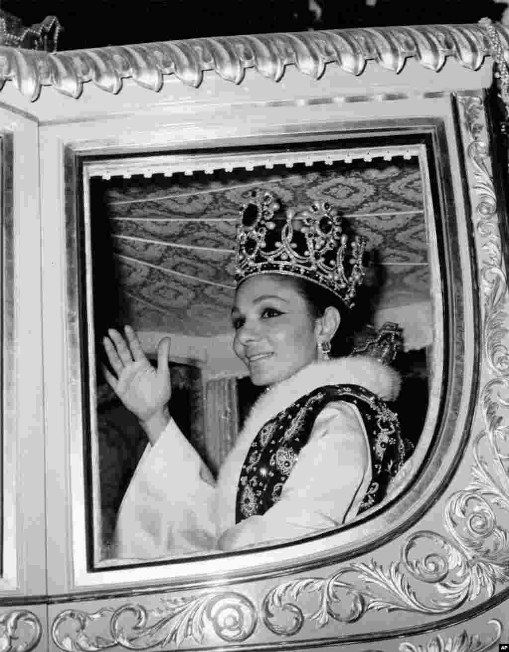 Empress Farah, wife of the shah of Iran, is pictured wearing her crown as she waves to crowds while driving through the streets of Tehran following their coronation ceremony on October 26, 1967.&nbsp;