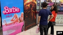 Moviegoers stand in front of the poster for the movie Barbie at a cineplex in Islamabad on July 21.