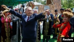 Then-Kazakh President Nursultan Nazarbaev dances with artists during celebrations to mark People's Unity Day in Almaty on May 1, 2016.